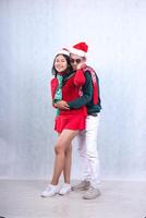 full body Two Asian people wearing Santa hats and warm clothes, standing hugging from behind happily and touching cheeks, celebrating Christmas and New Year isolated on white background photo
