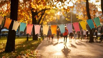 Colorful banners hang in park during autumn, creating festive atmosphere. People walk in background, enjoying vibrant fall scenery photo