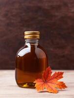 Maple syrup bottle with autumn leaf photo