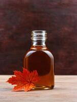 Autumn maple leaf and maple syrup bottle photo