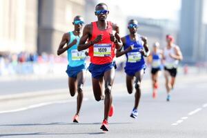 Group of runners in dynamic motion crossing the finish line in vibrant red and blue sportswear during a competitive outdoor race photo