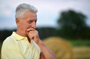 Serious senior man thinking in park on green background photo