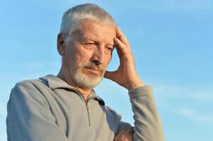 Portrait of a serious senior man on sky background. photo