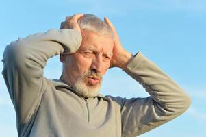 Portrait of a serious senior man on sky background. photo