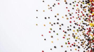 Colorful peppercorns scattered on white background photo