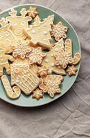 Christmas cookies with white icing forming various shapes lying on a plate photo