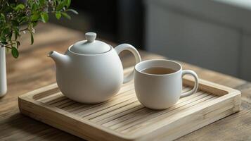 A white teapot and mug on a wooden tray photo