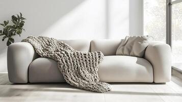 A white couch with a blanket on it in front of a window photo
