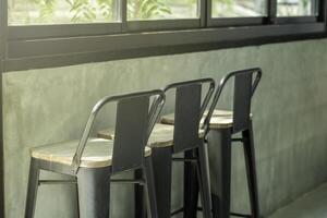 Bar stool in the loft style shop near the window glass with morning sunshine from outside. Window bar stools in cafes. photo