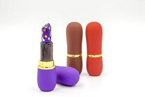 Three color lipstick, white background, Purple lipstick brush with gold glitter stars spilling out isolated on white background. photo