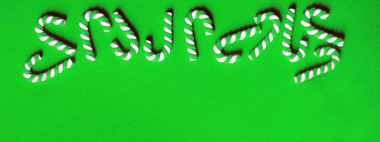 Christmas composition with frame of candy canes on a green background. photo