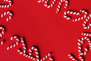 Flat lay Christmas composition with frame of candy canes on a red background. photo