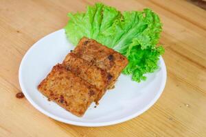 Tempe Bacem or Tempeh Bacem served on a white plate. Made from Tempeh cooked with special spices with a dominant sweet taste of brown sugar cooked by boiling photo