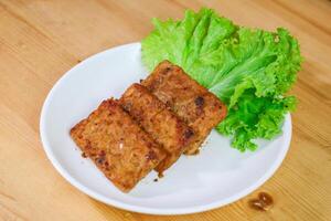 Tempe Bacem is a traditional food of Central Java, the tempeh is flavored with brown sugar and then fried, served on wicker bamboo plate photo