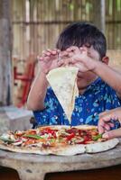 pequeño niño disfruta comiendo Pizza. foto