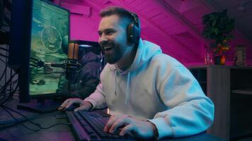 Laughing happy Caucasian vlogger presenter man male streamer playing online game using computer cyber sport at home influencer gamer streaming broadcast guy blogger celebrate rejoice win match addict video