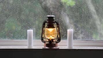 Relaxing Christmas scene with lit lantern and ditches and rain running down the window pane video