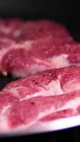 Close up, Juicy Piece of Pork Steak on Bone in Frying Pan with Boiling Oil. Texture. Cooking meat steak with a brown crispy crust, garlic, spices. Foam. Slow motion. Tasty dinner. Food background. video