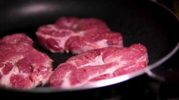 Close up, Juicy Piece of Pork Steak on Bone in Frying Pan with Boiling Oil. Texture. Cooking meat steak with a brown crispy crust, garlic, spices. Foam. Slow motion. Tasty dinner. Food background. video