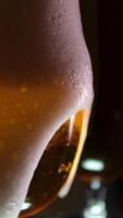 Process of filling large beer glass is filled with frothy unfiltered beer, fluffy foam of which spills over rim, close up. Man's hand holds full pint of beer. video