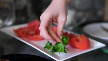 Tomato slices on a white plate Freshly sliced tomatoes arranged on a white plate with tongs, ready for serving in a kitchen setting, illuminated by warm lighting video