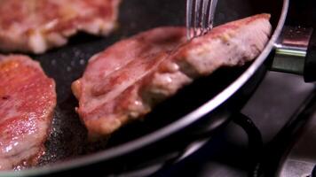 Three marbled beef steaks are fried in a frying pan on stove in the kitchen. video