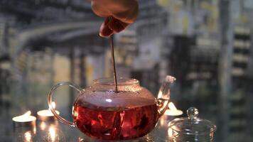 and stir red hibiscus tea with a spoon in a glass teapot on a dark background by candlelight process of making red hibiscus tea from sudanese rose flowers in a glass teapot video