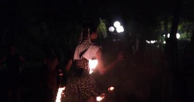 twists a long rope with a flame at the end and throws it far in different directions. Fire show artist video