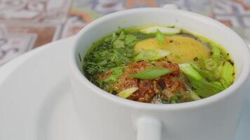 Chicken soup with potato and herbs spinning round on table video