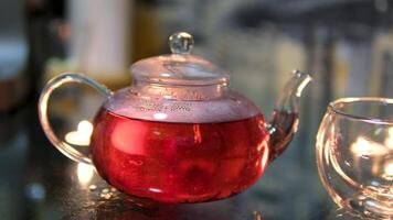 Cinemagraph shot of pouring hot tea from glass teapot into the mug with herbs and lemon. Warm and homey scene video