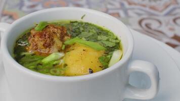 Chicken soup with potato and herbs spinning round on table video