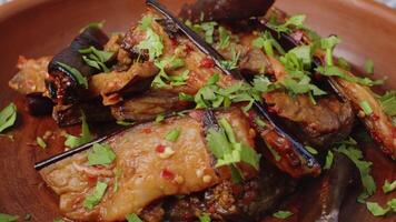 Salad with fried eggplant in clay plate spinning round on table video