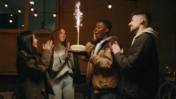 Friends celebrate with a sparkling cake at a cozy gathering in a beautifully lit venue during a memorable evening video