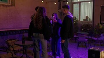 Group of friends enjoying a toast at a cozy outdoor gathering in the evening under string lights video