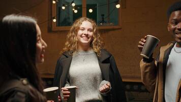 Friends enjoying a cozy evening gathering with lights and warm drinks in a charming outdoor space during autumn video