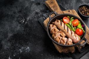 cena con ensalada y A la parrilla Cerdo salchichas en un sartén. negro antecedentes. parte superior ver foto