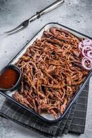 Pulled beef meat with hot chili sauce in baking dish. Gray background. Top view photo