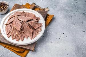 Corned sliced beef meat in a plate. gray background. top view photo