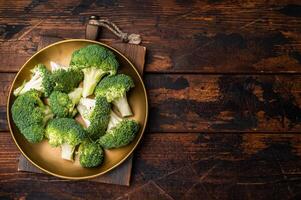 Fresh broccoli cabbage pieces on a plate. wooden background. top view photo