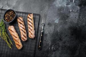 BBQ Grilled beef and pork sausages on steel rack. black background. top view photo
