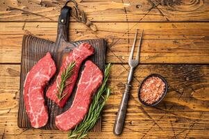 Raw marbled beef Steak, beef meat on wooden board with herbs. wooden background. top view photo