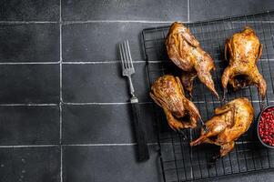 Grilled whole quails with herbs and spices. Black background. Top view. Copy space photo