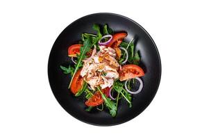 Salad with roasted salmon fillet steak, fresh salad arugula and tomato in a plate. Isolated, white background. Top view. photo