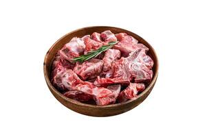 Fresh Raw meat on the bone diced for goulash in a wooden plate. Isolated on white background. Top view. photo