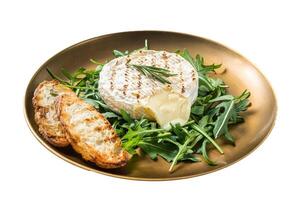 Salad with grilled Camembert cheese, arugula, toast and rosemary in a plate. Isolated on white background. Top view. photo