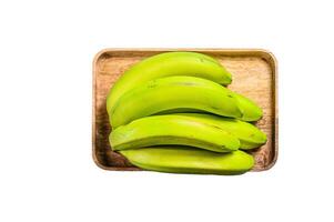 Green bananas on a wooden tray. Isolated on white background. photo