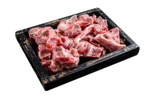 Raw diced meat with bone in a wooden tray. Isolated on white background. Top view. photo