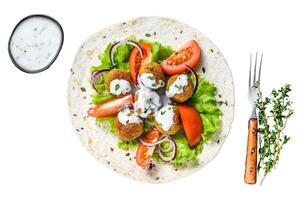 Vegetarian falafel with vegetables and tzatziki sauce on a tortilla bread. Isolated on white background, top view. photo