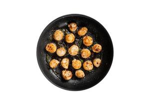 Fried scallops with butter lemon sauce in a skillet. Isolated on white background. photo