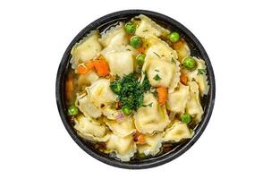 Broth soup with ravioli dumplings pasta in a pan. Isolated on white background. photo
